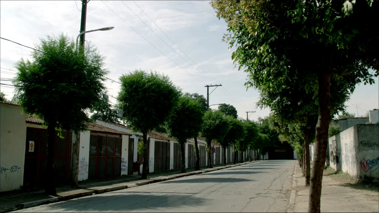 Rua residencial com grafites e casas convertidas, característica do bairro